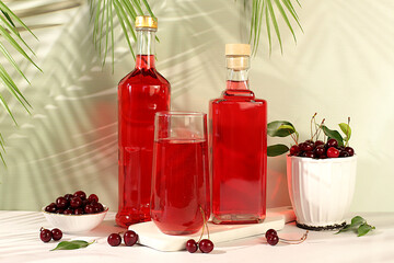 Homemade strong cherry cider in bottles and glasses on elegant background, still life with...