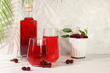 Homemade strong cherry cider in bottles and glasses on elegant background, still life with...