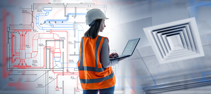 Female engineer in safety vest and helmet works with laptop on ventilation system design and blueprints, concept of HVAC, construction, engineering. Construction, Engineering, HVAC.