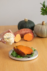 A woman prepares a dish with baked sweet potatoes and cream cheese. 
