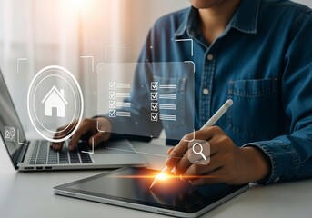 A young Asian male working on a digital tablet, managing tasks with a laptop in a modern workspace, emphasizing productivity.