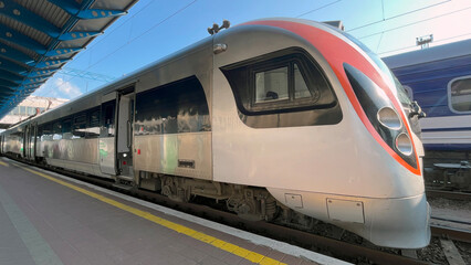 Fototapeta premium Modern train waiting at a busy station in daylight, showcasing sleek design and vibrant colors