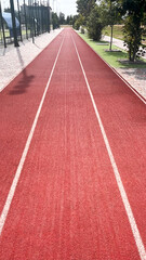 Running track stretches into the distance under bright sunlight in a public sports facility