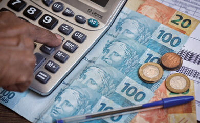 Brazilian currency. Brazilian reais notes on a table with a calculator, bills, and a pen. Concepts...