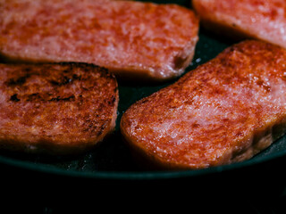Frying canned luncheon meat in a skillet 
