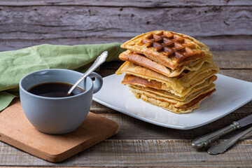 Breakfast consisting of a stack of waffles and a cup of coffee.