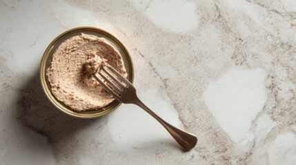Opened gourmet cat food can with fork on marble surface. Gourmet pate texture