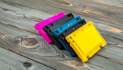 Colorful ink cartridges rest on a weathered wooden surface, showcasing primary printing colors.