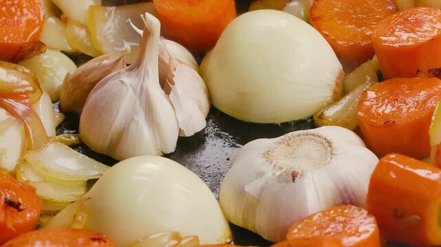 Panorama of onion halves and garlic being fried with vegetables in a frying pan. Close-up. High quality 4k footage