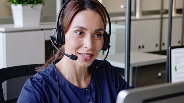 A smiling woman wearing a headset works in a call center