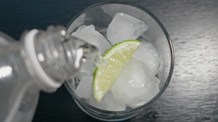 Pour tonic in glass with lime slice and ice - Powered by Adobe