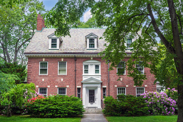 Stately Colonial Revival red brick family home framed by lush greenery in Brookline, Massachusetts, USA