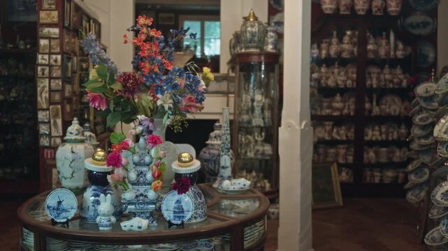 Antique store filled with various porcelain delft items and vibrant decorative flowers on display against a backdrop of vintage pottery collection.