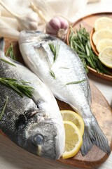 Fresh raw dorado fish, lemon slices, rosemary and spices on white wooden table, closeup. Organic seafood