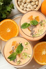 Superfood. Tasty smoothie with chia seeds, mint, pistachio and oranges on white wooden table, flat lay
