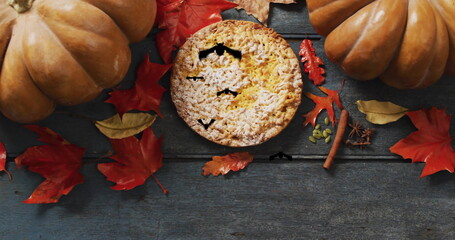 Pumpkin pie and autumn leaves with falling leaves image over wooden background