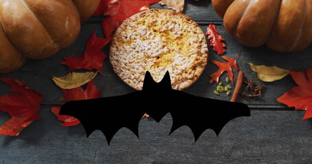 Bat image over autumn leaves, pumpkins, and pie on wooden background
