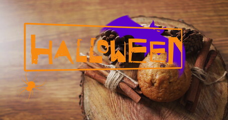 Halloween happy text image over muffin and cinnamon sticks on wooden surface