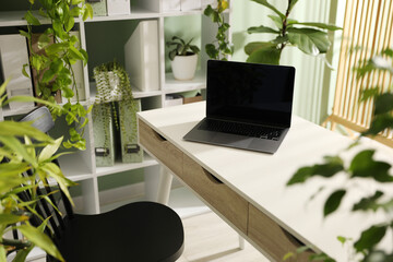 Biophilic interior design. Stylish workplace with laptop and houseplants in office