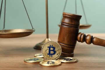 Cryptocurrency. Bitcoins, judge's gavel and scales on wooden table, closeup