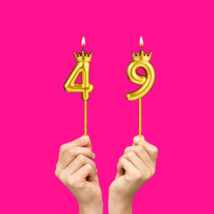 Hands holding number-shaped candles - Birthday number 49