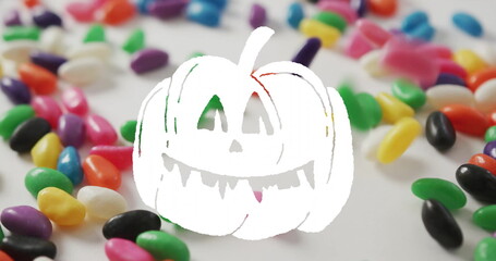 Jack-o-lantern image over colorful jelly beans scattered on white background
