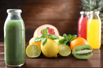 Tasty juices in glass bottles, fresh fruits, mint and basil on wooden table, selective focus