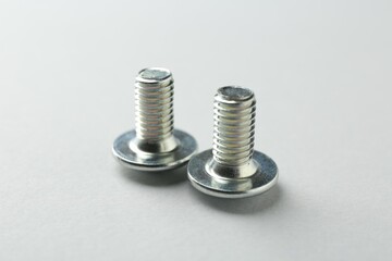 Two metal bolts on light grey background, closeup. Hardware tool
