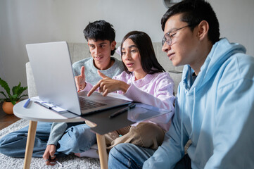 Students collaborating on a project using laptop at home