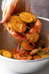 Korean cucumber salad (Oi muchim) mixing in bowl by hand, Korean side dish