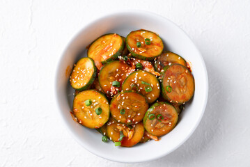 Top view of Korean cucumber salad (Oi muchim) in bowl on white background, Korean side dish
