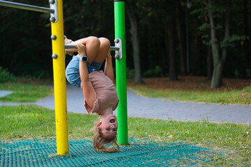 Girl playing upside down on playground equipment