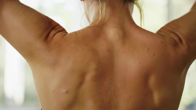 Woman's bare back, view from behind, with green background