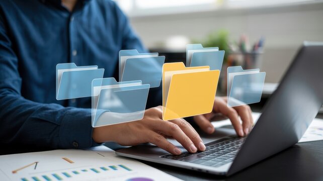 A person is typing on a laptop with floating file folders, representing data management, organization, and digital document storage