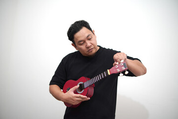 Asian man playing ukulele at home