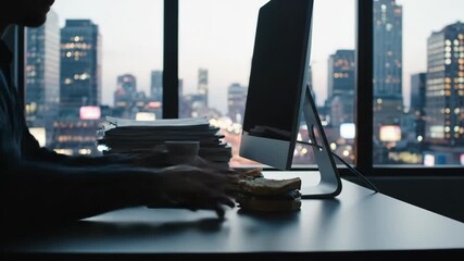 Person works at desk near window, city view