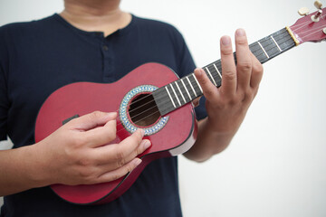 Asian man playing ukulele at home
