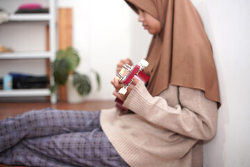 Asian muslim woman playing ukulele