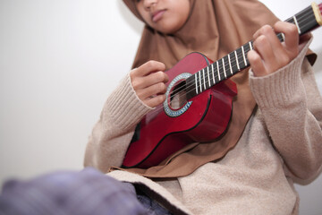 Asian muslim woman playing ukulele