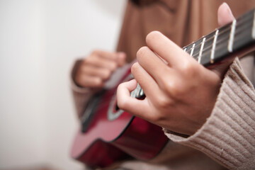 Asian muslim woman playing ukulele
