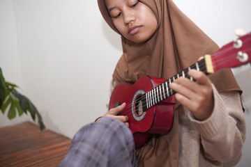 Asian muslim woman playing ukulele