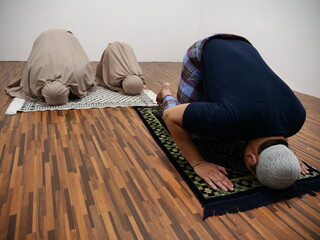 Asian muslim man doing shalat pray with his daughters, sujud