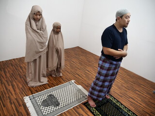 Asian muslim man doing shalat pray with his daughters