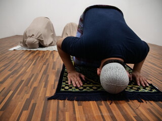 Asian muslim man doing shalat pray with his daughters, sujud