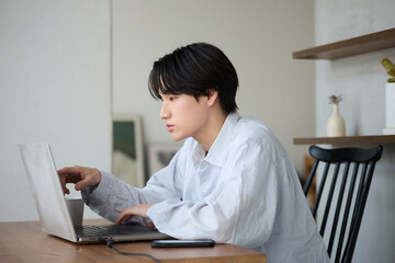 自宅で仕事をしているアジアの若い男性