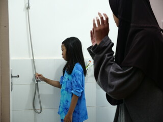 Asian muslim girl teaching her little sister to do wudu or ablution, cleaning before salat prayer
