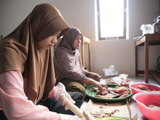 Indonesian muslim woman preparing meals in kitchen with her daughter, cooking traditional authentic asian food