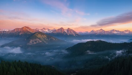 Obraz premium Aerial view of mountain range with snow capped peaks and valley filled with fog at sunrise or sunset