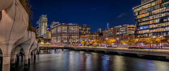 Naklejka premium The illuminated Little Island park at Pier 55 with a futuristic design and a lit-up cityscape reflecting on the Hudson River in New York, USA