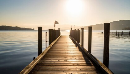 Obraz premium Wooden pier stretches into a calm lake at sunrise, bathed in golden light